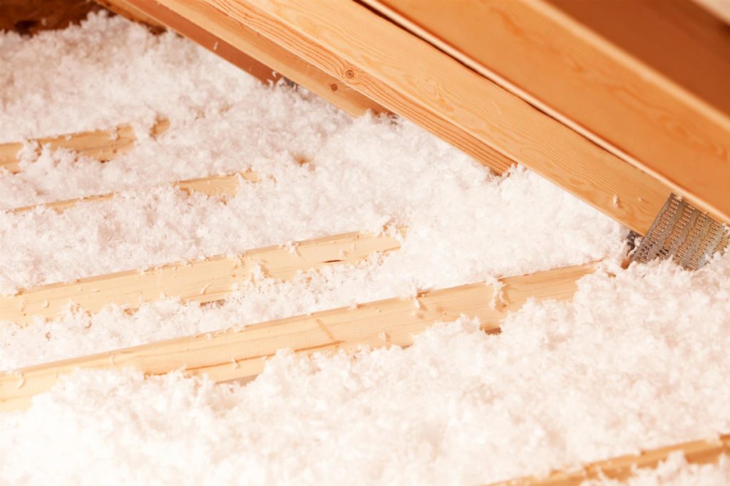 White loose-fill fiberglass insulation installed in an attic floor.