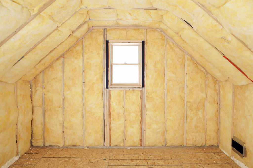 An attic with yellow insulation and a window.